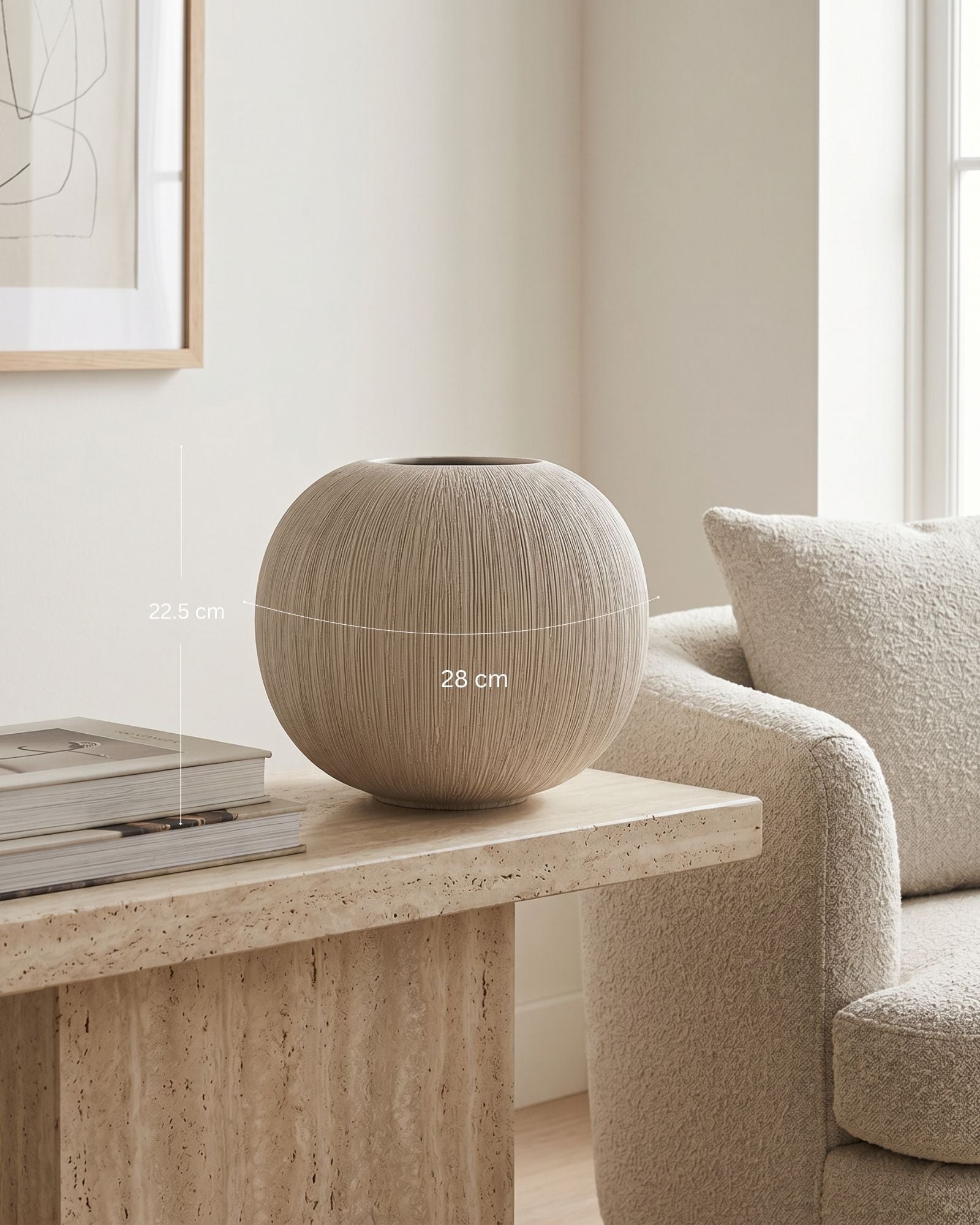 Round beige vase on a wooden table with a sofa and window in the background