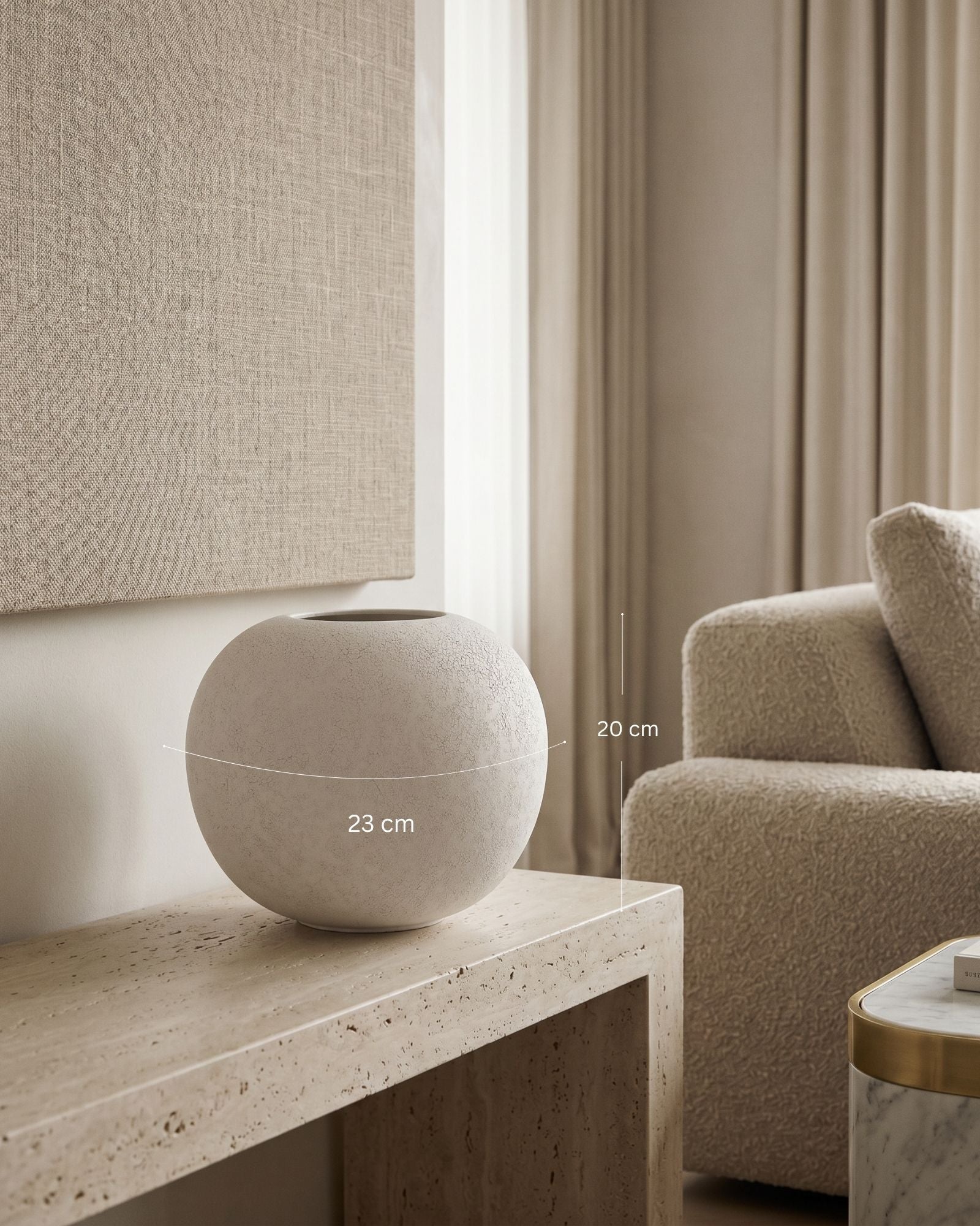 Beige textured vase on a wooden table with a sofa and curtains in the background