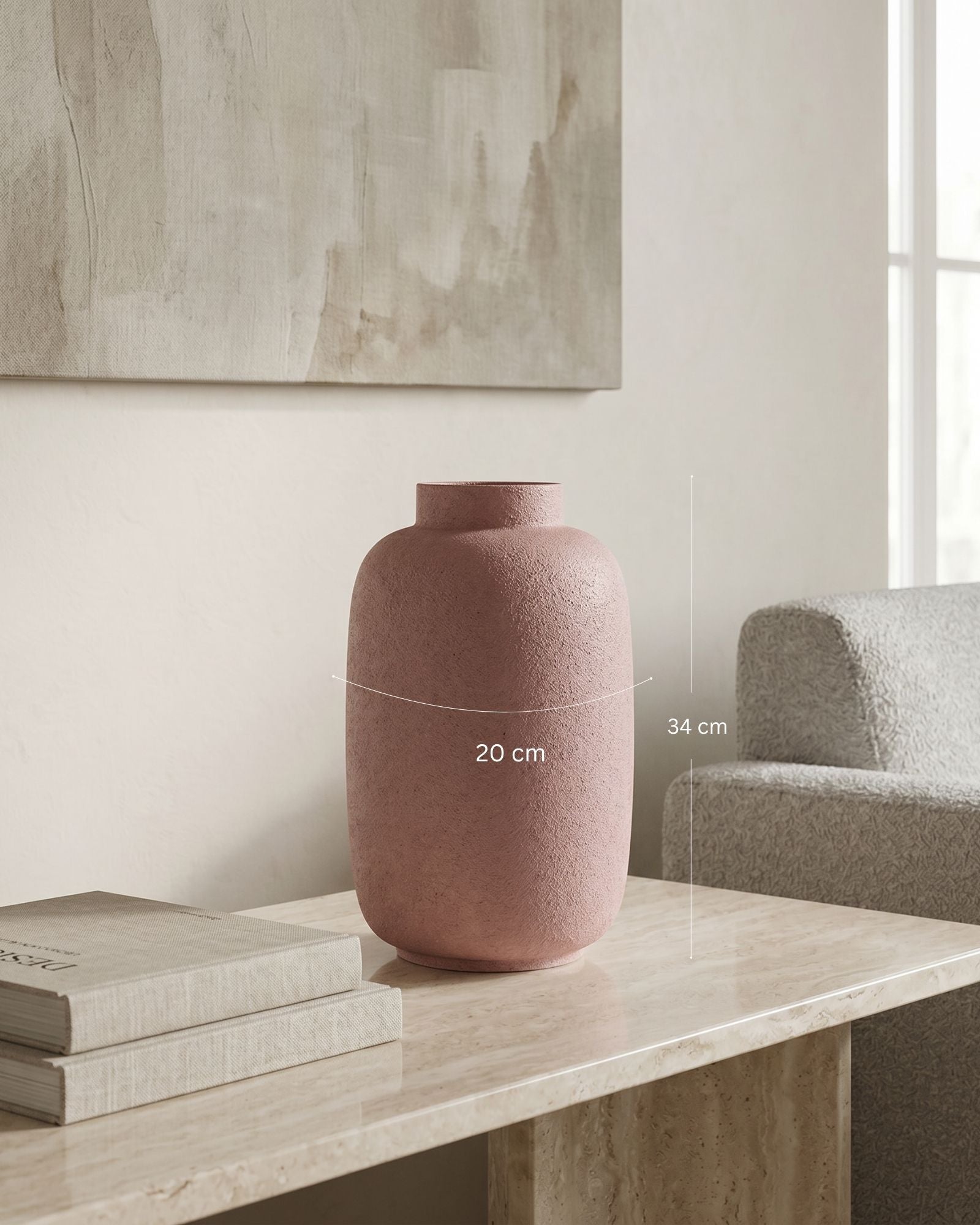 Pink textured vase on a table with books, against a neutral wall.